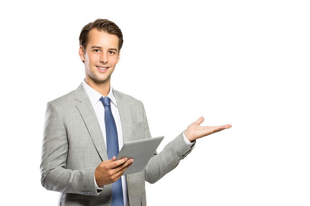 young businessman holding a tablet and presenting copyspace - Valokuva, kuva