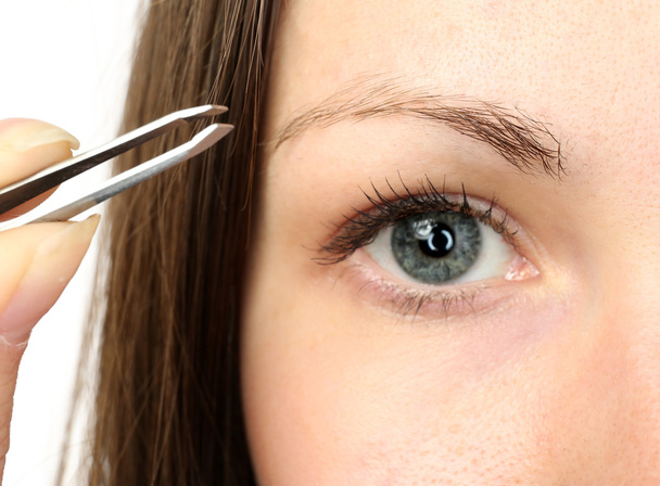 woman plucking eyebrows with tweezers - Фото, зображення