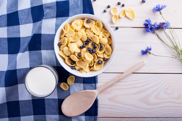 flocos de milho com mirtilo, xícara de leite, flor e colher
 - Foto, Imagem