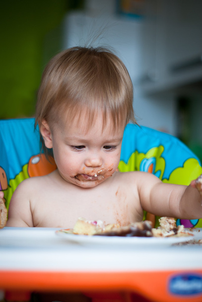 Gyermek megeszi tortát a magasszékben - Fotó, kép