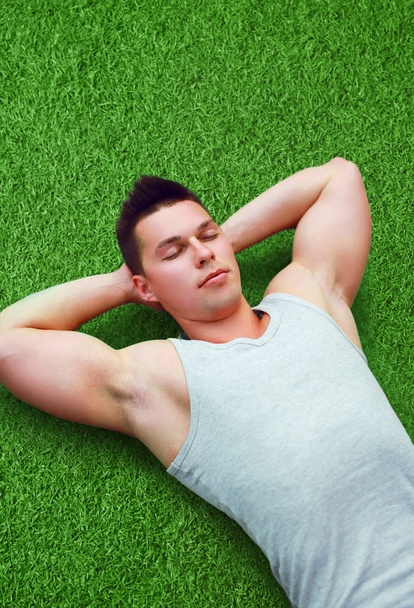 Portrait of handsome sporty fitness young man relaxing on the gr - Foto, Imagen