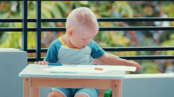 Toddler boy scatters crayons and paper - Felvétel, videó