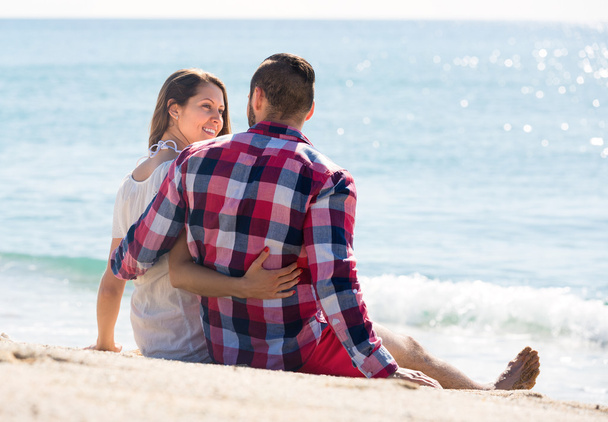 Amante casal sentado na areia da praia
 - Foto, Imagem