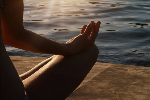 Hand of woman meditating in a yoga pose on beach - Photo, Image