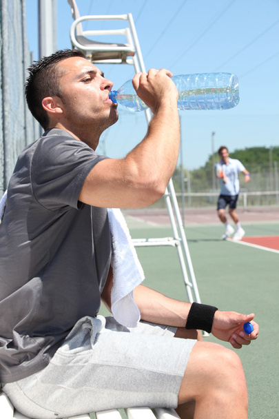 Man drinking water on tennis court sideline - Foto, Imagem