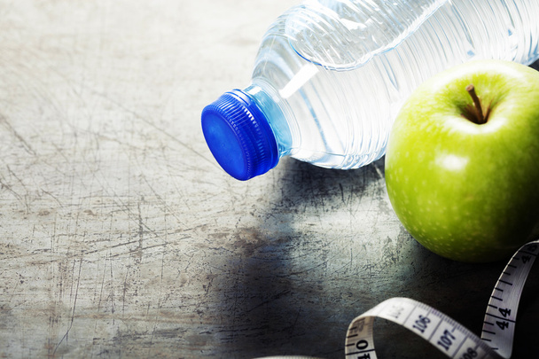 Green apple, water and measuring tape. Health and diet concept - Foto, afbeelding