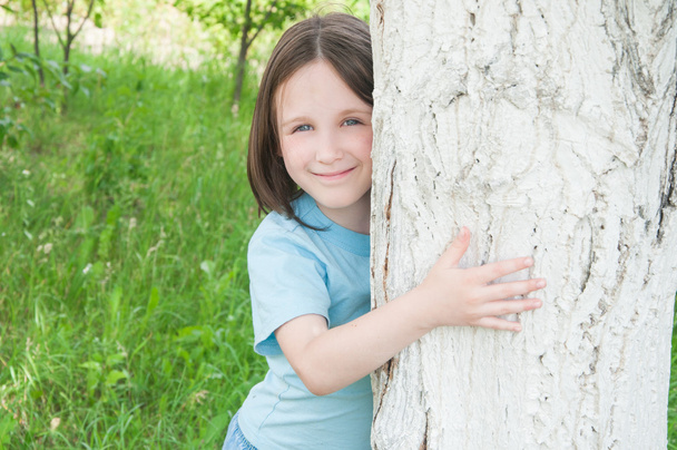 girl looks out from behind a tree - Foto, immagini
