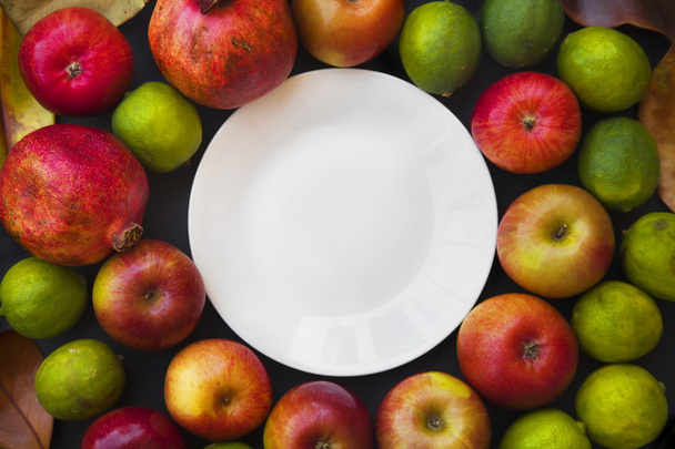 Background with round plate, apples and limes - Foto, Bild