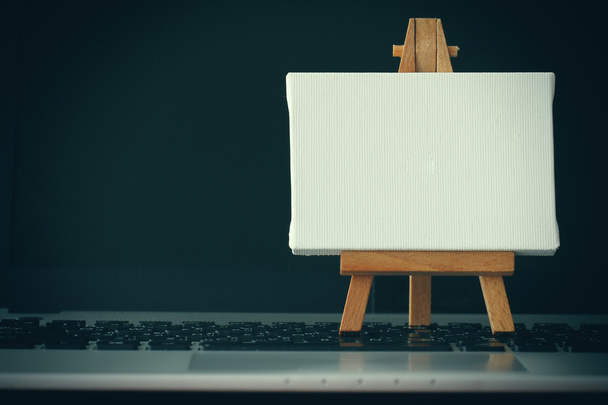 blank canvas and wooden easel on laptop computer as concept - Fotografie, Obrázek