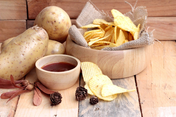 Potato chip and fresh potatoes on wood background - Fotó, kép