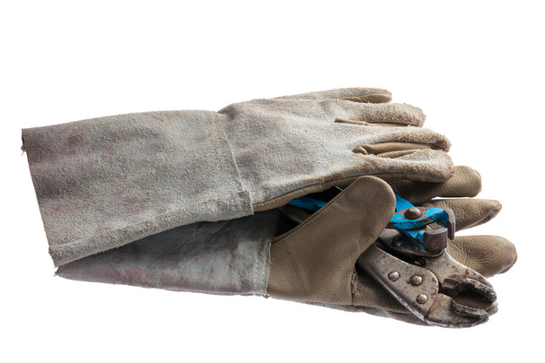Oude lederen werkhandschoenen met moersleutel geïsoleerd op witte achtergrond - Foto, afbeelding