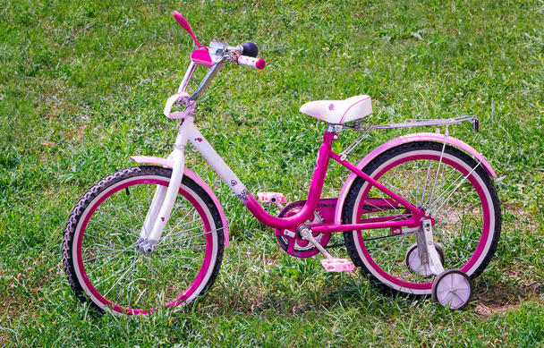 το ποδήλατο για το κορίτσι για ένα πράσινο γκαζόν. - Φωτογραφία, εικόνα