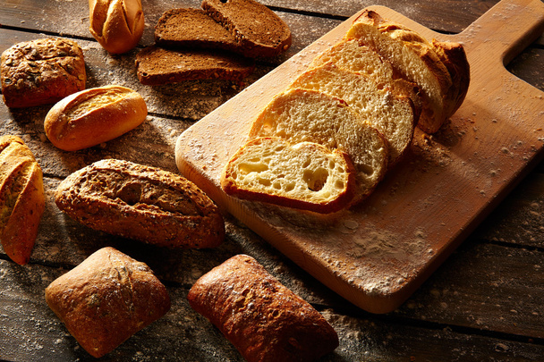 Bread varied loafs sliced on wood board in rustic - Фото, изображение