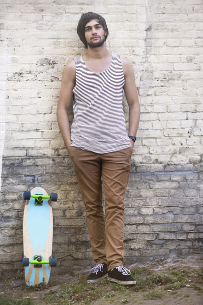 Jistý americký skateboardista, opíraje se o zeď - Fotografie, Obrázek