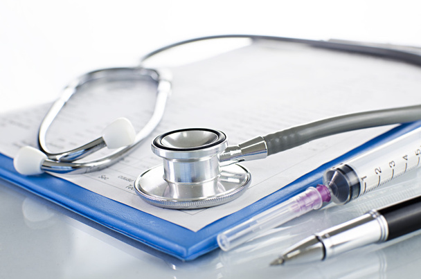 Krankengeschichte auf Klemmbrett mit Stethoskop auf hellem Hintergrund - Foto, Bild