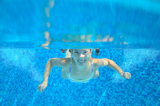 Happy child swims in pool underwater, active kid swimming, playing and having fun, children water sport - Valokuva, kuva