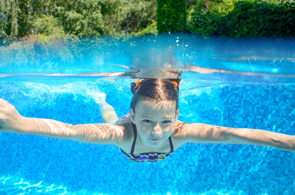 Happy child swims in pool underwater, active kid swimming, playing and having fun, children water sport - 写真・画像