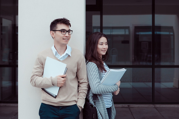 Two attractive students talking and standing Outside Building of campus - 写真・画像
