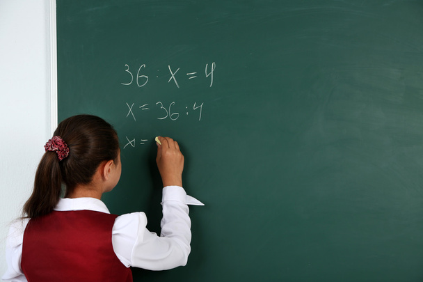 Beautiful little girl writes on blackboard in classroom - Foto, Imagem
