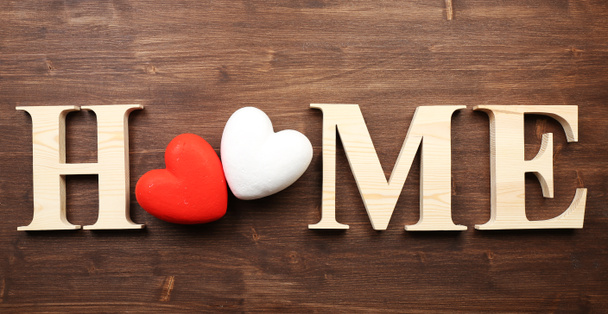 Lettres décoratives formant le mot HOME avec des cœurs sur fond en bois
 - Photo, image