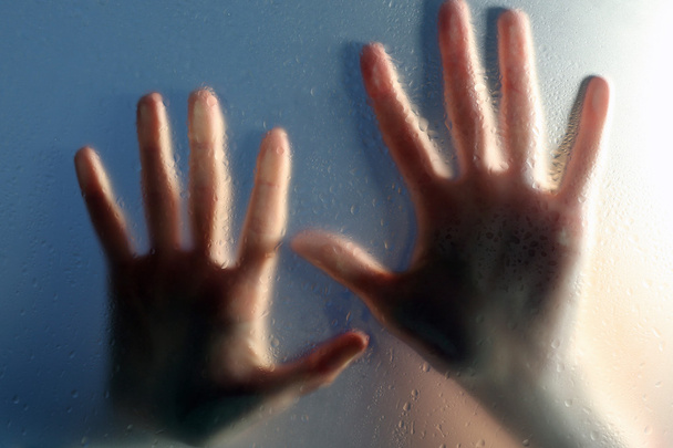 Female hands behind  wet glass, close-up - Zdjęcie, obraz