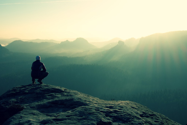 Turysta siedzi na skalisty szczyt i cieszyć się w scenerii gór - Zdjęcie, obraz