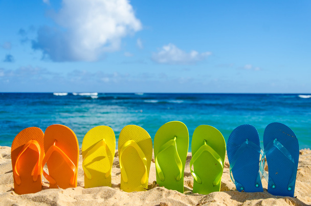 Chanclas de colores en la playa de arena
 - Foto, imagen