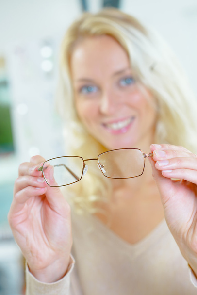 Woman holding spectacles to foreground - Foto, immagini