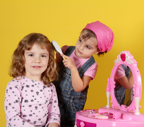 Дві маленькі дівчата грають у перукарні
 - Фото, зображення