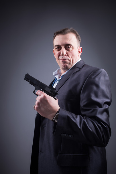 man in a business suit with a gun - Фото, изображение