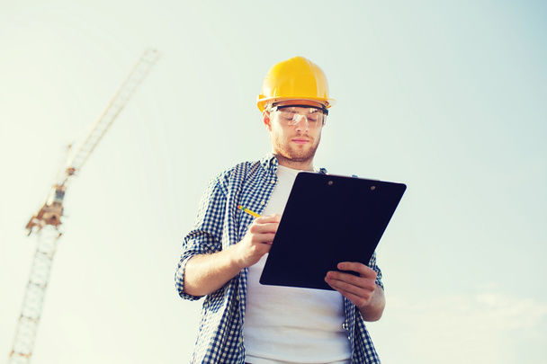 builder in hardhat with clipboard outdoors - Foto, Imagem