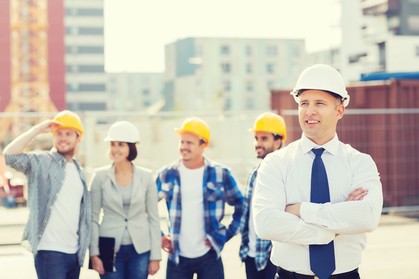 group of smiling builders in hardhats outdoors - Foto, immagini