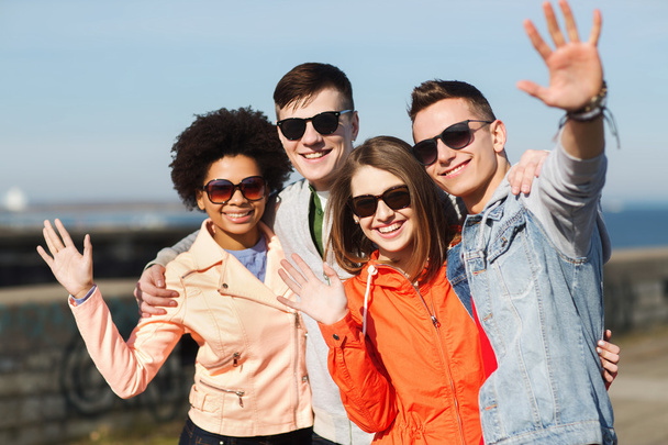 happy teenage friends in shades waving hands - Фото, зображення