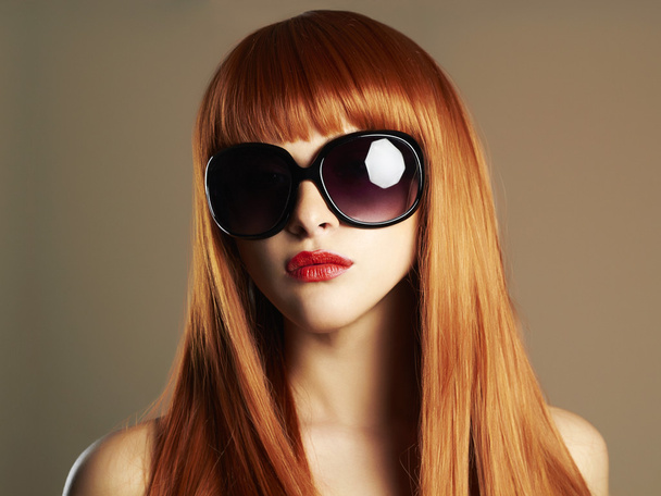 Красавица в солнечных очках. Здоровые рыжие волосы. Красивая молодая женщина с красными губами
 - Фото, изображение