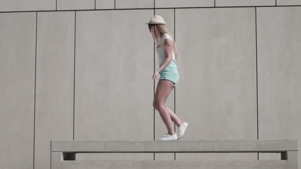 Energiegeladene junge Frau im Fitness-Outfit, die an einem Springseil vor weißem Wandhintergrund bei sonnigem Klima übt. - Filmmaterial, Video