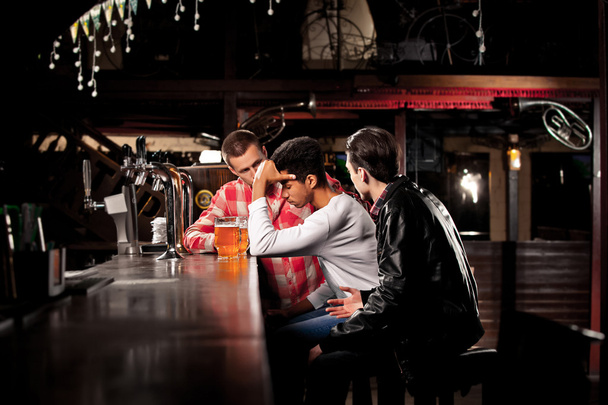 друзі п'ють пиво і проводять час разом у барі
. - Фото, зображення