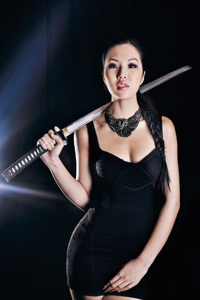 Hermoso modelo en vestido elegante negro con espada
 - Foto, imagen