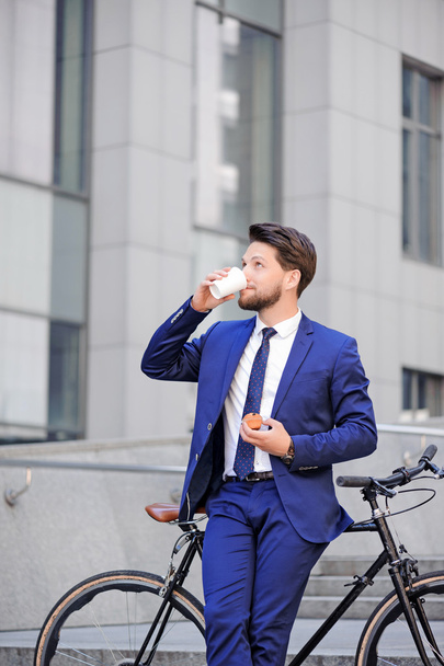 Pleasant businessman standing with bicycle  - Photo, Image