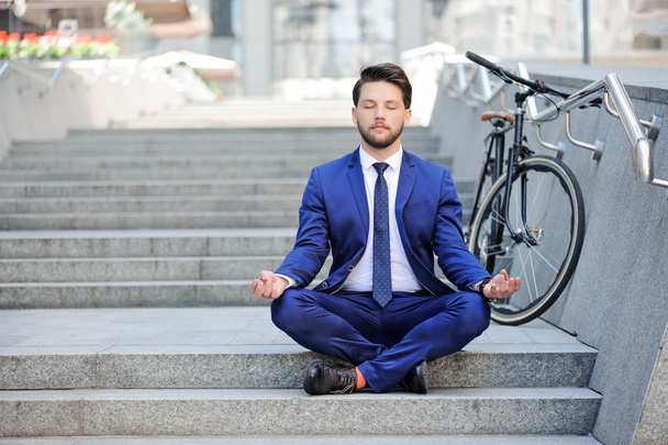 Young businessman practicing yoga on stairs.  - Foto, imagen