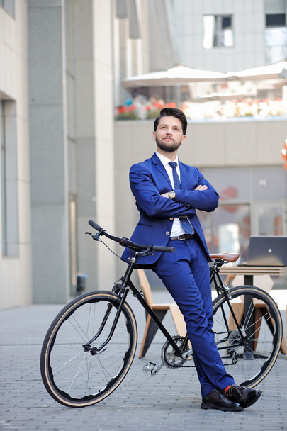 Nice businessman leaning on bicycle - Foto, afbeelding