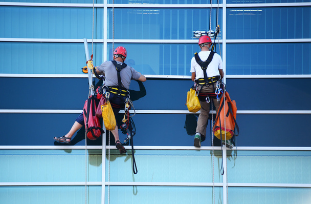 Zwei Bauarbeiter arbeiten in luftiger Höhe an Wolkenkratzer  - Foto, Bild
