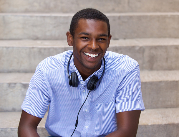 Szczęśliwy czarny facet siedzi ze słuchawkami - Zdjęcie, obraz