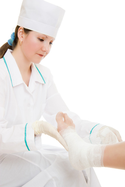 A woman doctor shakes his leg with a bandage on a white background. - Foto, Bild
