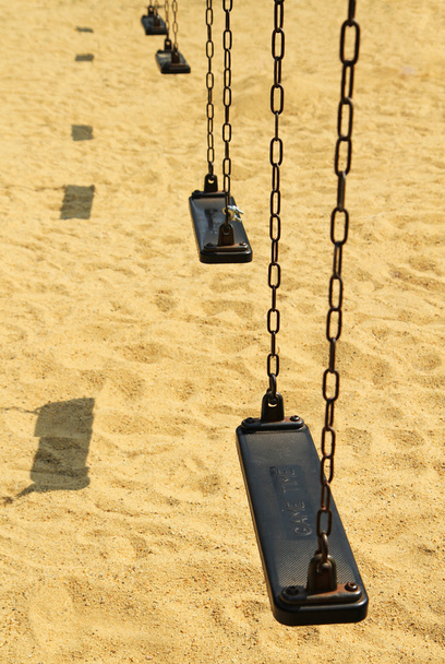 Empty old swing set on sand floor background - Photo, Image