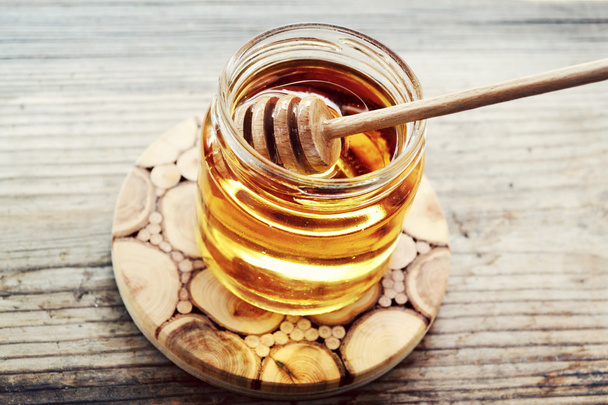 Miel dorada con palillo de miel. estrellas de canela y anís sobre mesa de madera
 - Foto, imagen