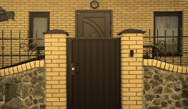 Puertas de metal moderna casa de ladrillo amarillo filtrado
 - Foto, imagen