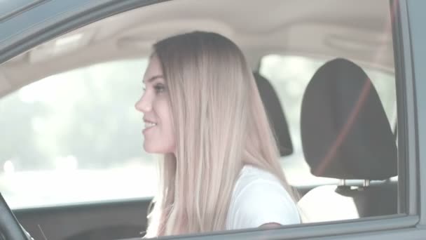 Kaunis nuori tyttö istuu autossa näyttää ajokortti uusi kuljettaja
 - Materiaali, video