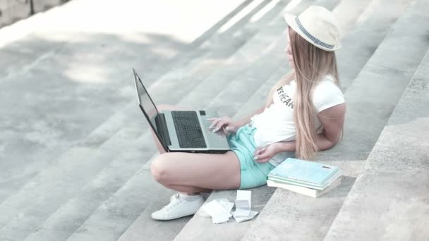 Mujer joven usando el ordenador portátil en los escalones al aire libre
 - Metraje, vídeo