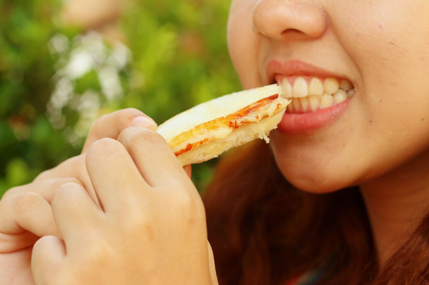 Woman eating a sandwich with ham and cheese. - Photo, Image