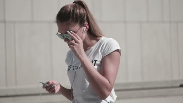 Aantrekkelijke jonge vrouw luisteren muziek op in de stad dragen van een zonnebril - Video